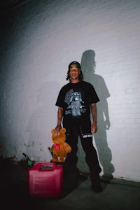 a man with a teddy bear standing in front of a wall